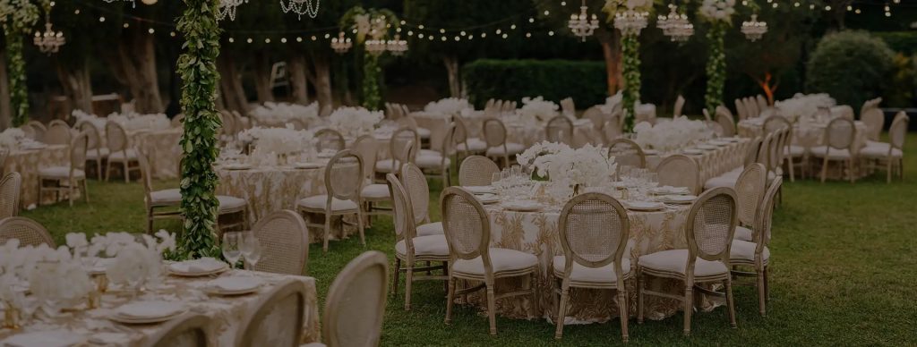 Modern ghost chairs and floral arch at an outdoor event – Florida Event Rentals

